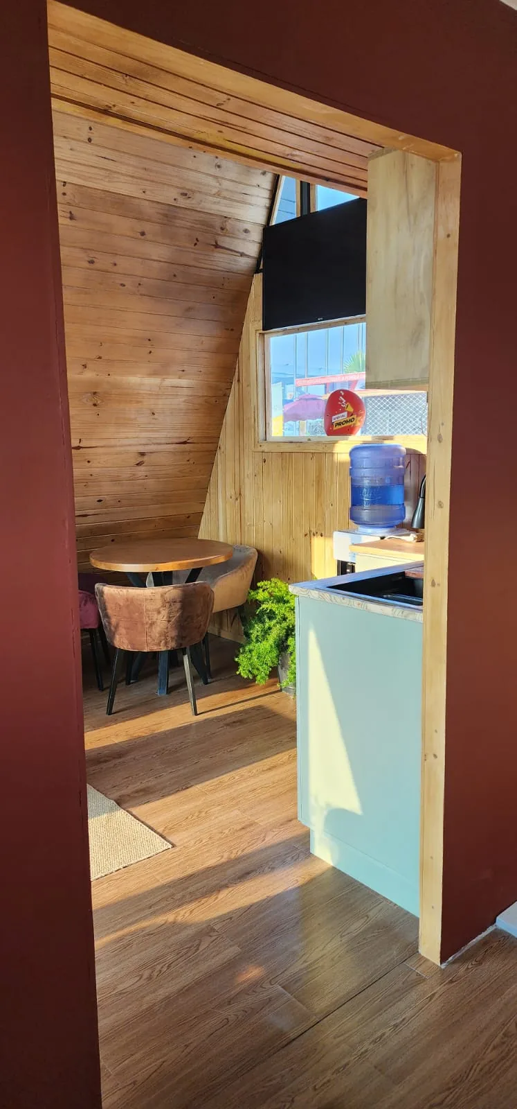 Coin repas avec table ronde en bois et chaises en velours sous la pente du toit