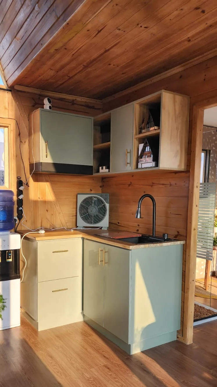 Kitchenette sur mesure vert sauge, plan de travail bois et évier noir